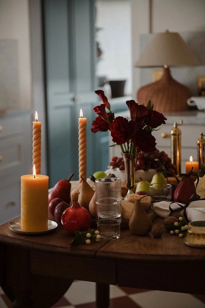 Candlelit dining table with pears, red dahlias and glassware